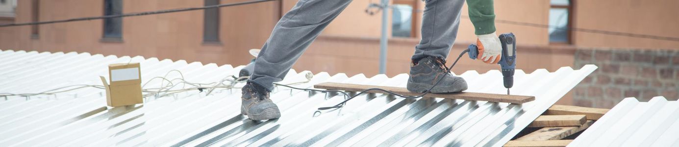 Lapos tetőn dolgozó bádogos tetőfedő tető bádogozás közben, szakszerű bádogos javítás családi házon.